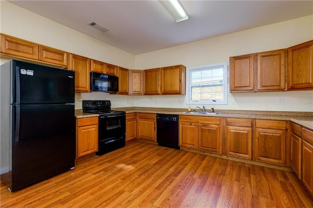 kitchen featuring sink, black appliances, and light hardwood / wood-style floors