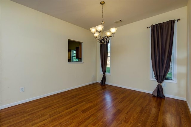 unfurnished room with a notable chandelier, hardwood / wood-style flooring, and a healthy amount of sunlight