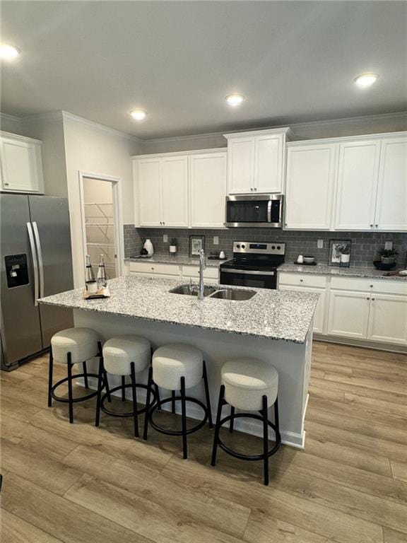 4005 Riverchess Dr SW, Atlanta, GA 30331 - kitchen with a center island with sink, a breakfast bar area, white cabinets, and appliances with stainless steel finishes