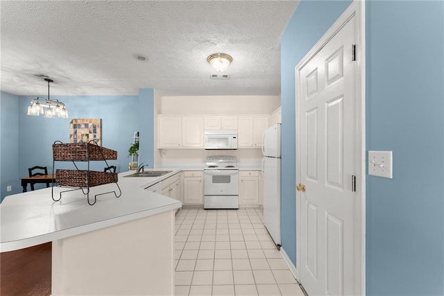 kitchen featuring white appliances, visible vents, a peninsula, a sink, and light countertops