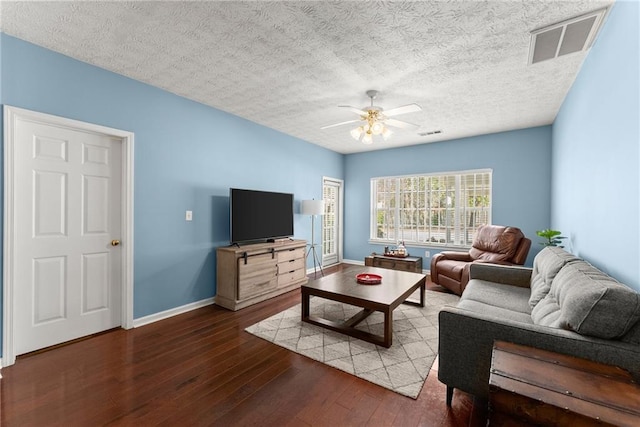 living area featuring visible vents, wood-type flooring, baseboards, and a ceiling fan