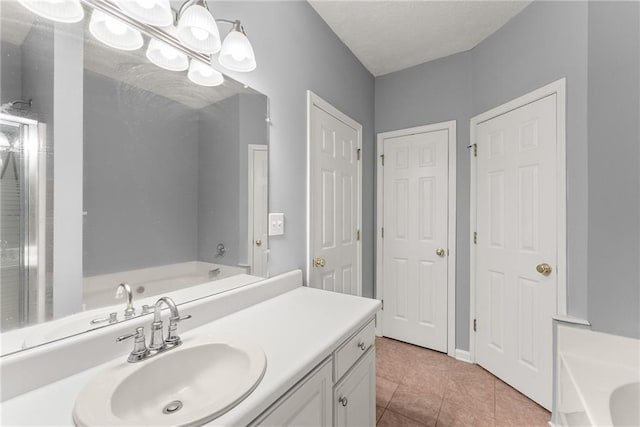 full bath with vanity, a garden tub, tile patterned floors, and a textured ceiling