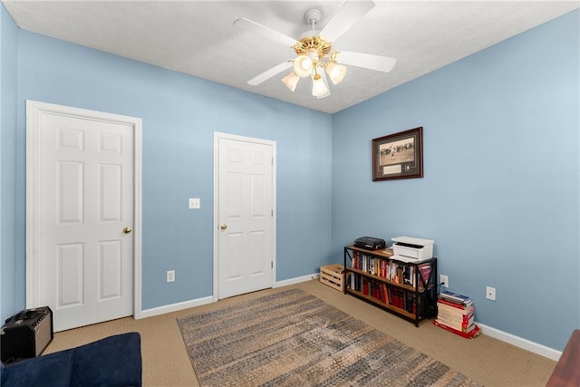 interior space with a textured ceiling, baseboards, ceiling fan, and carpet floors