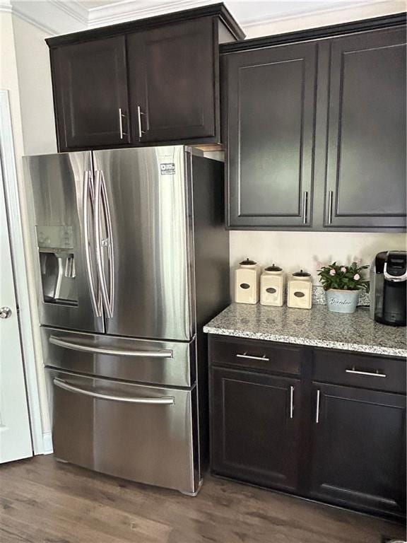 kitchen with stainless steel refrigerator with ice dispenser, dark wood-type flooring, light stone counters, and crown molding