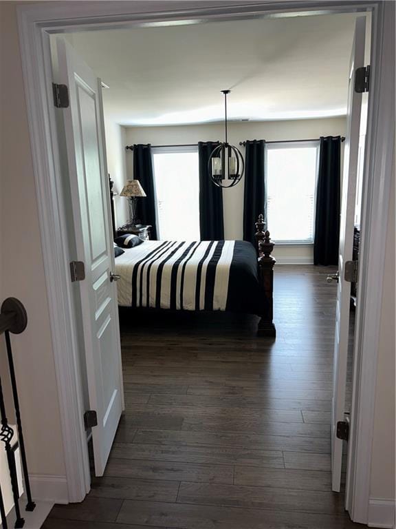 bedroom with an inviting chandelier and dark hardwood / wood-style floors