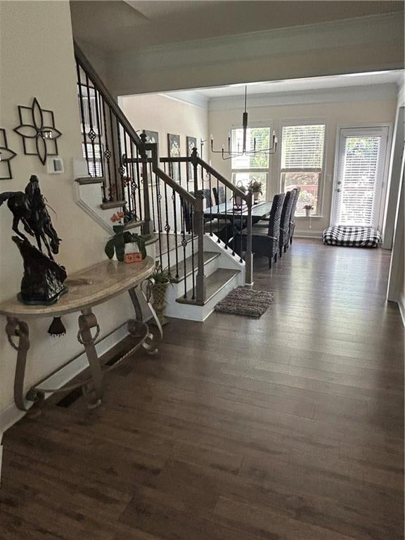 stairs with hardwood / wood-style floors, a notable chandelier, and ornamental molding