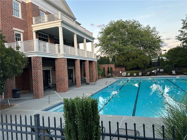 pool at dusk with a patio area