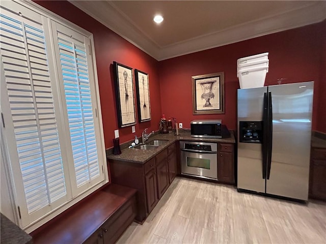 kitchen featuring sink, ornamental molding, stainless steel appliances, and light wood-type flooring