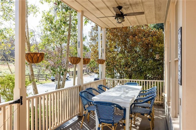 wooden terrace with outdoor dining area and a ceiling fan