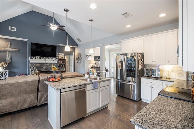 kitchen with light stone counters, an island with sink, white cabinets, and appliances with stainless steel finishes