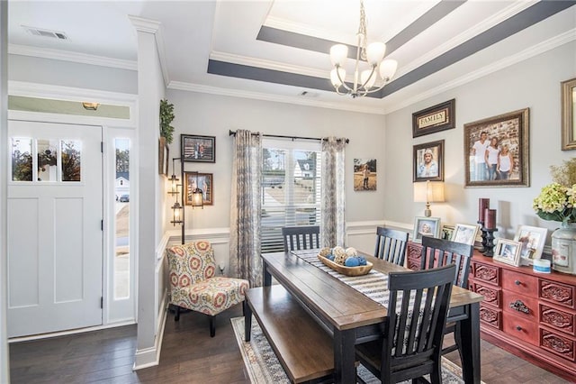 dining room with dark wood-type flooring, ornamental molding, a tray ceiling, and a notable chandelier