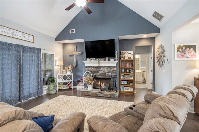 living room featuring ceiling fan, a stone fireplace, high vaulted ceiling, and dark hardwood / wood-style flooring