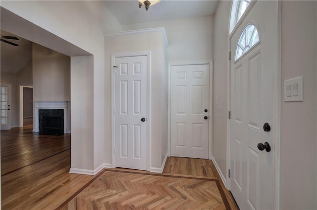 foyer entrance featuring a premium fireplace, light parquet flooring, and ceiling fan