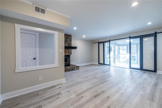 6700 Roswell Rd Unit 21E, Sandy Springs, GA 30328 - unfurnished living room featuring crown molding, wood finished floors, recessed lighting, a stone fireplace, and a barn door