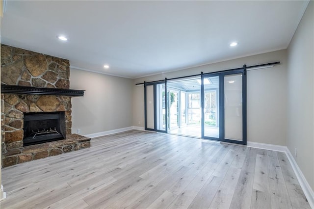 6700 Roswell Rd Unit 21E, Sandy Springs, GA 30328 - unfurnished living room with crown molding, wood finished floors, a barn door, a stone fireplace, and recessed lighting