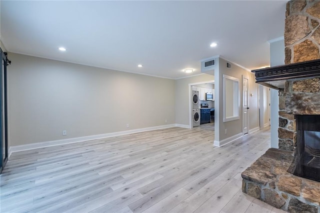 6700 Roswell Rd Unit 21E, Sandy Springs, GA 30328 - living area featuring ornamental molding, stacked washer / dryer, light wood-type flooring, a stone fireplace, and recessed lighting