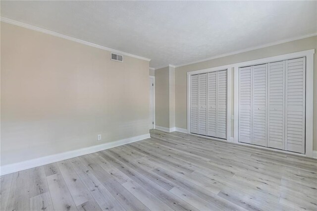 6700 Roswell Rd Unit 21E, Sandy Springs, GA 30328 - unfurnished bedroom with two closets, light wood-style flooring, and ornamental molding