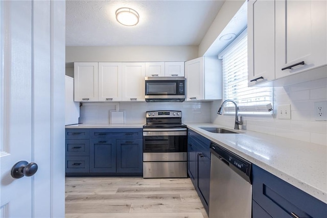6700 Roswell Rd Unit 21E, Sandy Springs, GA 30328 - kitchen featuring appliances with stainless steel finishes, blue cabinetry, white cabinets, and light stone countertops