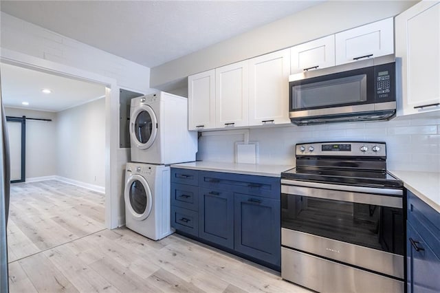 6700 Roswell Rd Unit 21E, Sandy Springs, GA 30328 - kitchen with appliances with stainless steel finishes, stacked washing machine and dryer, a barn door, light countertops, and white cabinets