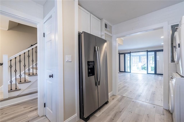 6700 Roswell Rd Unit 21E, Sandy Springs, GA 30328 - kitchen with stainless steel refrigerator with ice dispenser, stacked washer / drying machine, white cabinetry, and light wood finished floors