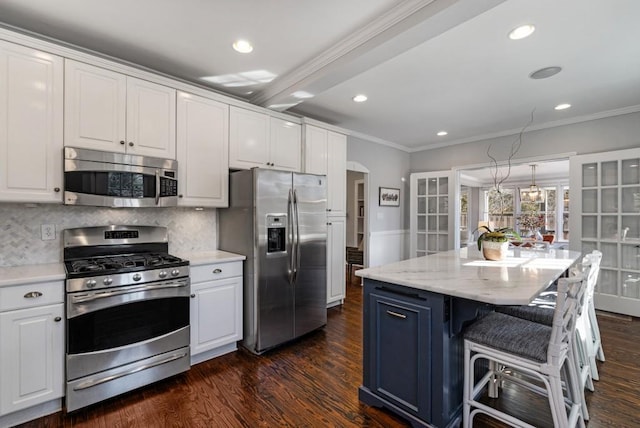 kitchen with arched walkways, stainless steel appliances, white cabinetry, ornamental molding, and dark wood finished floors