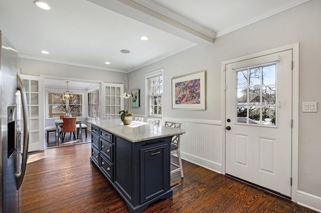 kitchen featuring dark wood finished floors, stainless steel fridge, plenty of natural light, and a kitchen bar