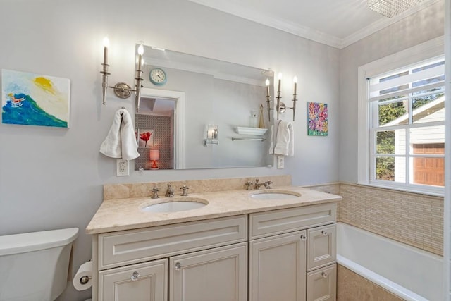 full bath featuring toilet, crown molding, double vanity, and a sink