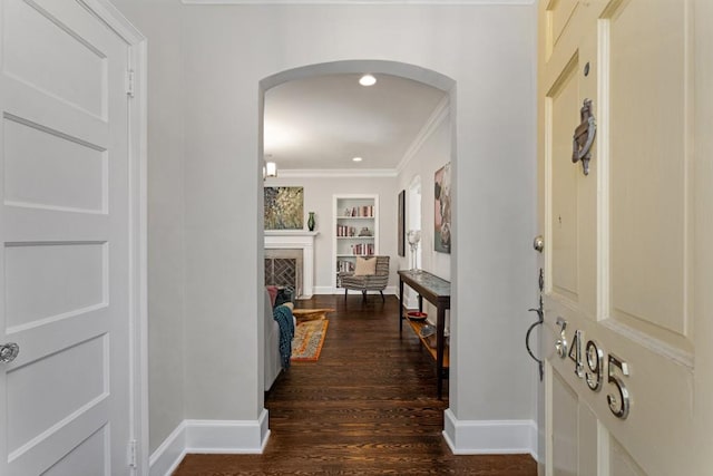 entryway with arched walkways, a fireplace, baseboards, ornamental molding, and dark wood-style floors