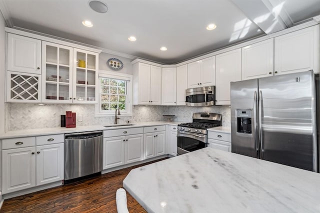 kitchen featuring stainless steel appliances, a sink, white cabinets, backsplash, and glass insert cabinets