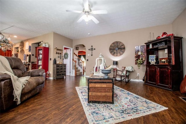 living area with stairs, arched walkways, a textured ceiling, wood finished floors, and ceiling fan with notable chandelier