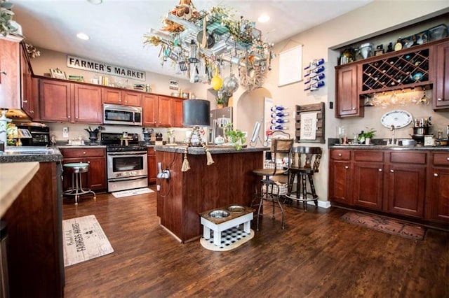 kitchen featuring stainless steel appliances, recessed lighting, dark wood-style flooring, and a kitchen breakfast bar