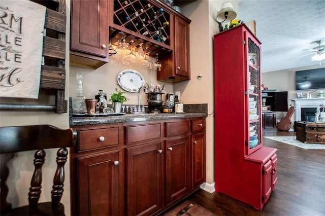 bar featuring ceiling fan, a textured ceiling, a fireplace, wet bar, and dark wood-style floors