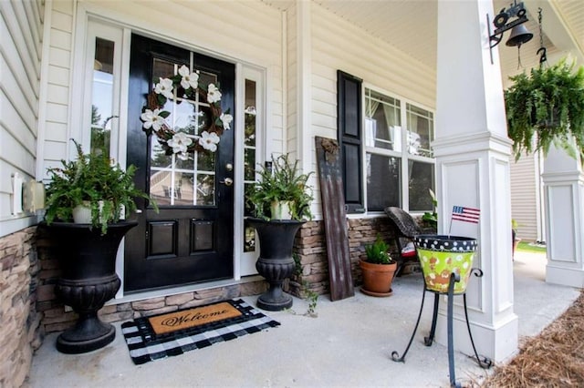 doorway to property with stone siding and a porch