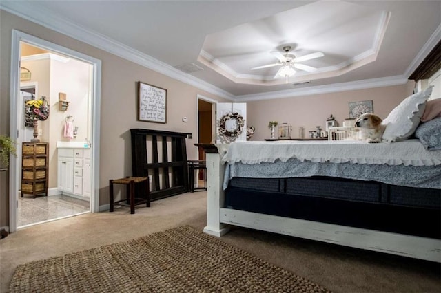 bedroom featuring ceiling fan, ornamental molding, ensuite bathroom, a tray ceiling, and carpet flooring