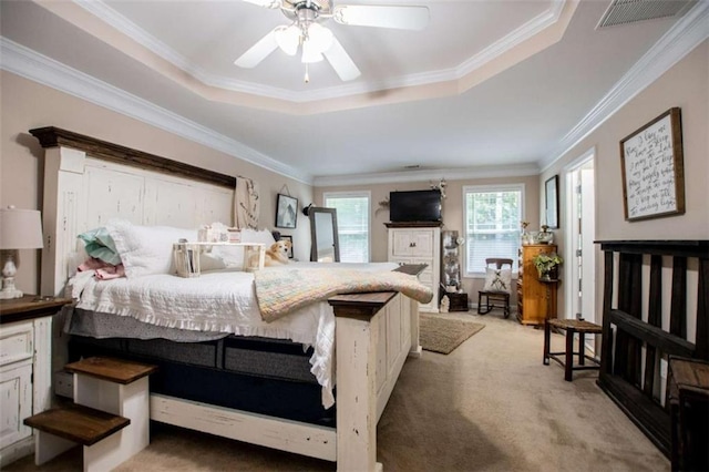 bedroom featuring a tray ceiling, visible vents, ornamental molding, light carpet, and ceiling fan