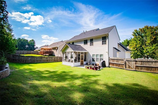 back of house featuring a sunroom, a fenced backyard, and a lawn