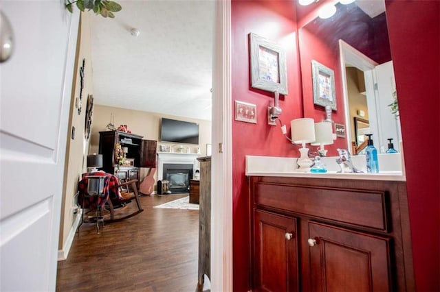 bathroom featuring a fireplace, wood finished floors, and vanity