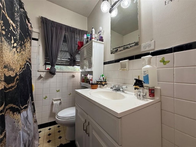 bathroom with tile walls, tile patterned floors, a wainscoted wall, vanity, and toilet
