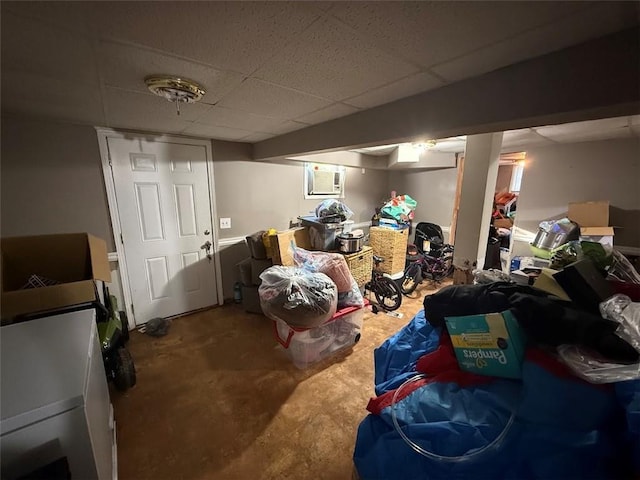 finished below grade area featuring a wall mounted AC, carpet flooring, and a paneled ceiling