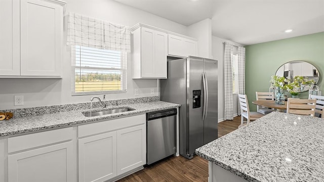 kitchen with light stone countertops, white cabinetry, appliances with stainless steel finishes, and sink