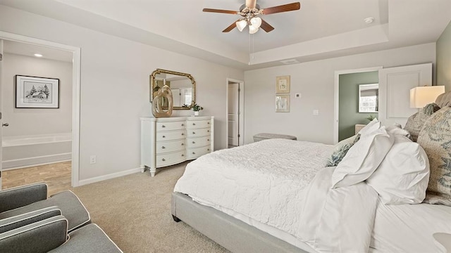 carpeted bedroom with connected bathroom, ceiling fan, and a tray ceiling