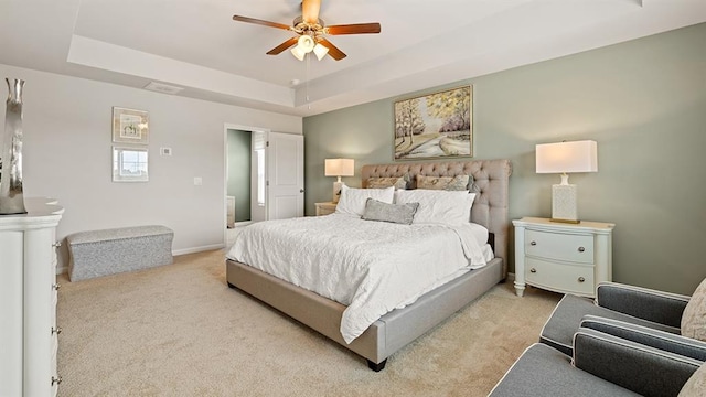 bedroom featuring ceiling fan, a raised ceiling, and light carpet