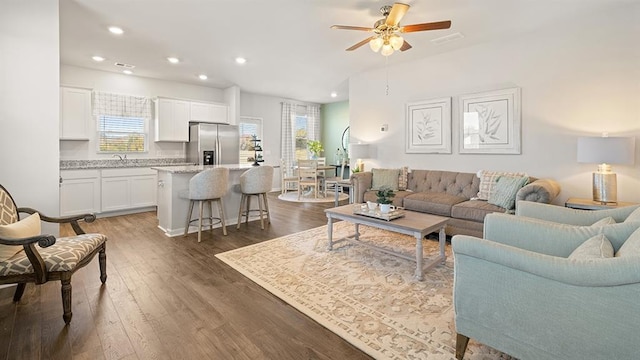 living room with dark wood-type flooring, sink, and ceiling fan