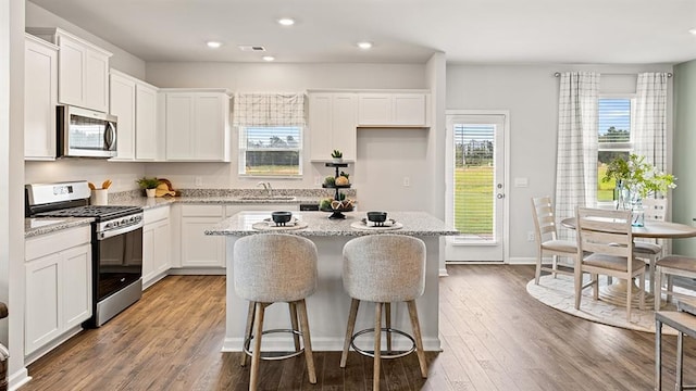 kitchen with sink, white cabinetry, light stone counters, a center island, and stainless steel appliances