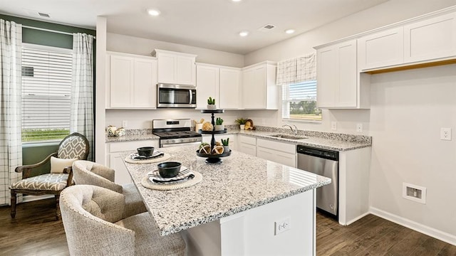 kitchen with stainless steel appliances, a center island, sink, and white cabinets