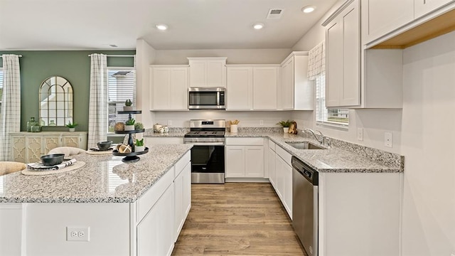 kitchen featuring white cabinetry, stainless steel appliances, light stone countertops, and sink