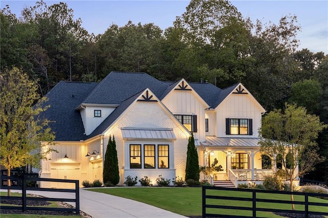 modern farmhouse style home with a garage, covered porch, and a front lawn