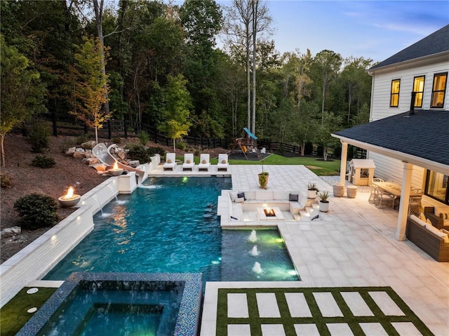 view of swimming pool with pool water feature, an in ground hot tub, a playground, a patio, and an outdoor living space with a fire pit