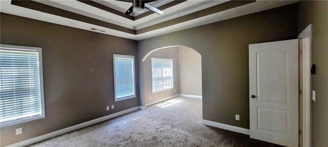 carpeted empty room with ornamental molding, a raised ceiling, and ceiling fan