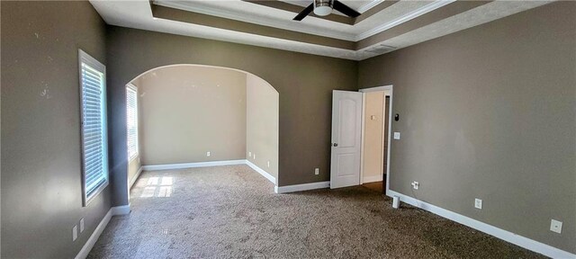 empty room featuring a tray ceiling, ornamental molding, ceiling fan, and carpet flooring